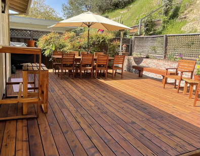 A backyard deck of a residential house with outdoor furniture and amenities.