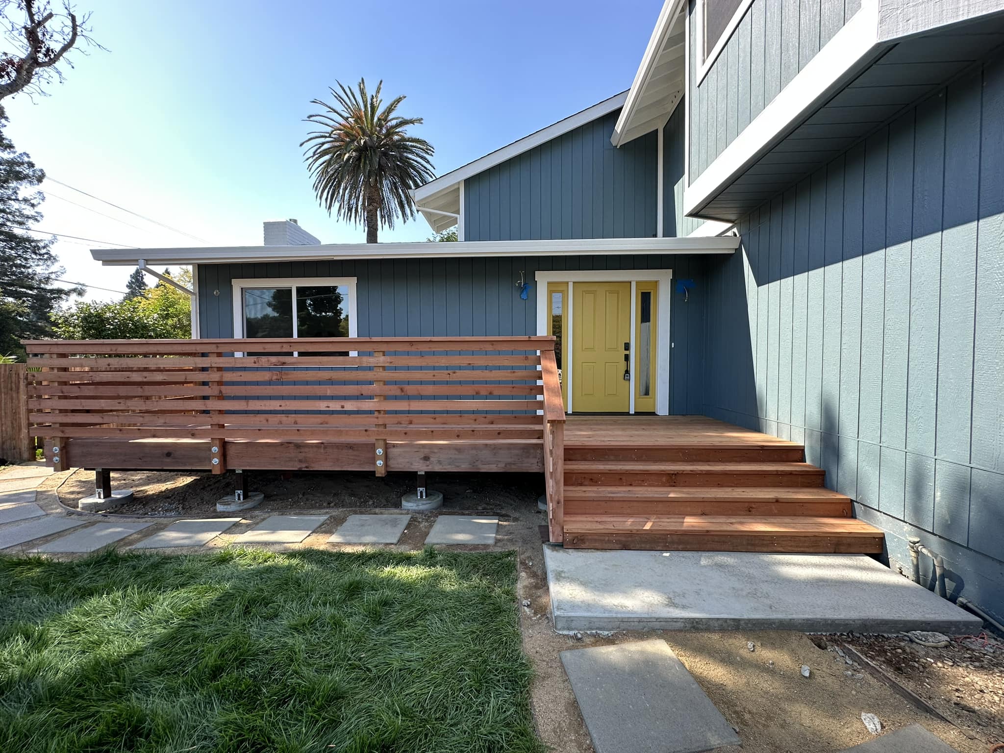 A deck wrapping around the side and front of a residential house.